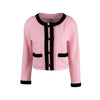Chanel pink wool bouclé tweed jacket with contrasting black trim. Short fit with a crew neck, long sleeves, and two patch pockets on the front. Decorated with black braided buttons with golden CC logo pre-owned nft
